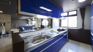 Une cuisine moderne avec des meubles bleus, un évier en acier inoxydable et une fenêtre avec des rideaux.