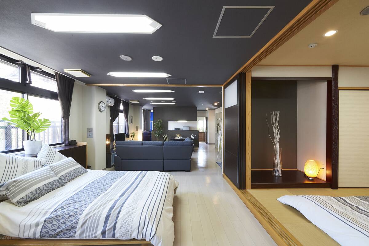 Habitación de hotel moderna con una cama grande, un sofá, un comedor y vistas de la ciudad.
