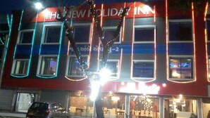 A building with a sign reading "NEW HOLIDAY INN" and a car parked in front. - The New Holiday Inn (Mahesana)