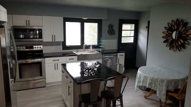 A modern kitchen with stainless steel appliances, a central island, and a dining area with a table and chairs.