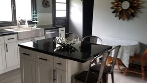 A modern kitchen with white cabinets, a black countertop, and a central island with bar stools.