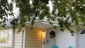 A house with a porch, two turquoise chairs, and a welcome sign.