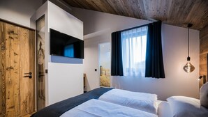 Une chambre à coucher avec un lit, une télévision, une armoire en bois et une fenêtre avec des rideaux.