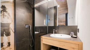 Une salle de bain moderne avec une douche, un lavabo et un miroir.