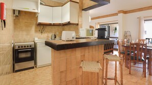 A kitchen with a central island, a dining area with wooden chairs, and a built-in oven. - Apartment 'A Casa E A Praia Da Ana' near the beach and historic center (Lagos)