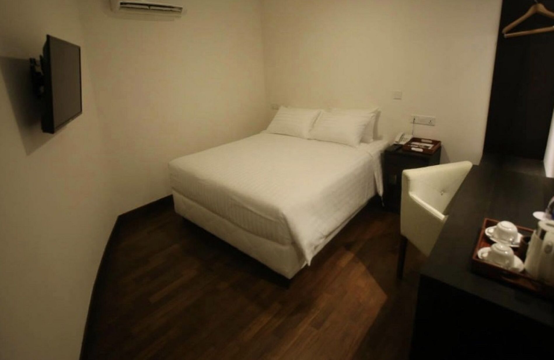 Habitación de hotel con cama, mesita de noche, silla y un escritorio pequeño con una taza y un plato.