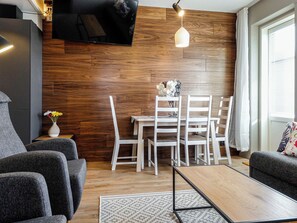 A modern living room with a flat-screen TV mounted on the wall, a dining area with white chairs and a table, and a sofa set. - Levin kunkku b8 by Interhome (Kittilä)