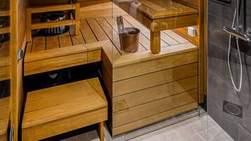 A modern sauna with wooden benches and a glass-enclosed shower area.