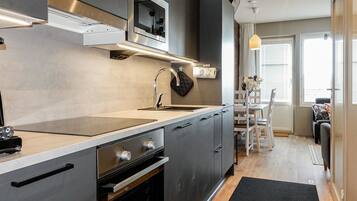 A modern kitchen with a built-in oven, a stainless steel range hood, and a large window providing natural light.