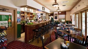 A bar area with a counter, chairs, and tables. There are signs advertising beer and prices. - Pointe Royale Condo retreat (Branson)