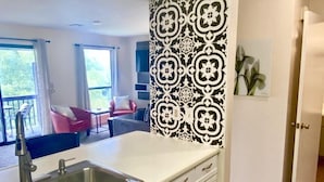 A modern kitchen with white cabinetry and a black and white patterned accent wall. - Pointe Royale Condo retreat (Branson)