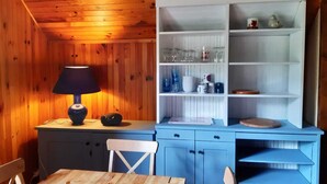 Een kamer met houten lambrisering, een blauwe kast, een tafel en een stoel.