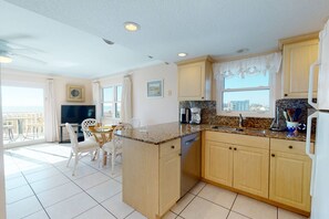 A spacious kitchen with a dining area, large windows, and a view of the sea.