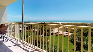 A balcony with a view of a beach and a well-maintained lawn. - Fabulous Location. Updated Beachfront Condo. Pool, Recreation Amenities, Comfortable! (Treasure Island)