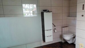 A bathroom with a toilet, a cabinet with drawers, and a window. - Ferienwohnung Reulecke (Blankenburg (Harz))