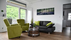 Una sala de estar moderna con un sofá gris, sillones verdes y una mesa de centro de madera.