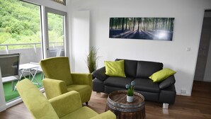 Una sala de estar moderna con un sofá, dos sillones, una mesa de centro y un cuadro en la pared.
