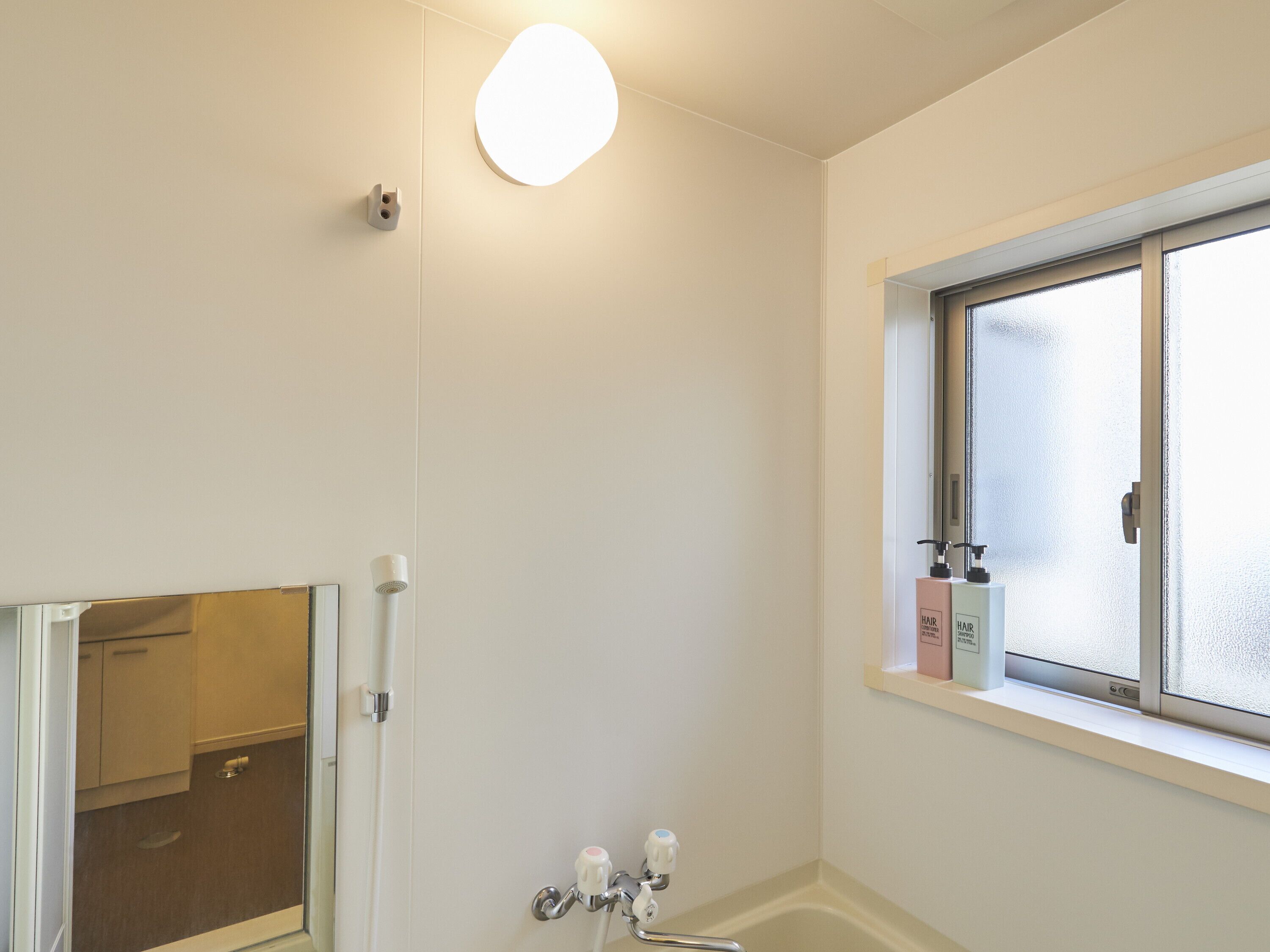 A bathroom with a toilet, a sink, a window, and a shower.