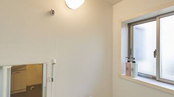 A bathroom with a toilet, a sink, a window, and a shower.