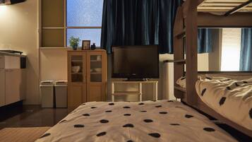 A room with a bunk bed, a desk with a computer, a television, and a window with curtains.