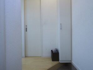 A hallway with a wooden floor, white walls, and a door with a handle. - Oyado Kinokuniya Daikoku Machi (Nagasaki)