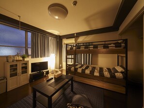 A compact room with bunk beds, a television, a desk, and a window with curtains. - Oyado Kinokuniya Daikoku Machi (Nagasaki)