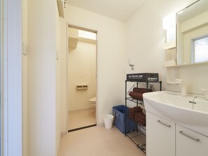 A small, compact bathroom with a toilet, sink, and storage shelves. - Oyado Kinokuniya Daikoku Machi (Nagasaki)