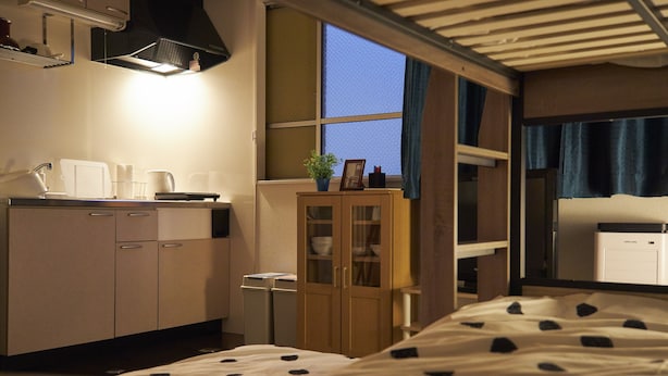 A hotel room with a bed, a small kitchenette, a cabinet, and a window with curtains. - Oyado Kinokuniya Daikoku Machi (Nagasaki)