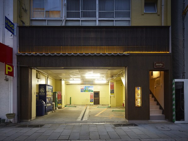 A building entrance with a parking sign, a coffee machine, and a staircase leading inside. - Oyado Kinokuniya Daikoku Machi (Nagasaki)