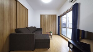 Una sala de estar moderna con un sofá seccional, una mesita con una planta y un mueble para televisor.