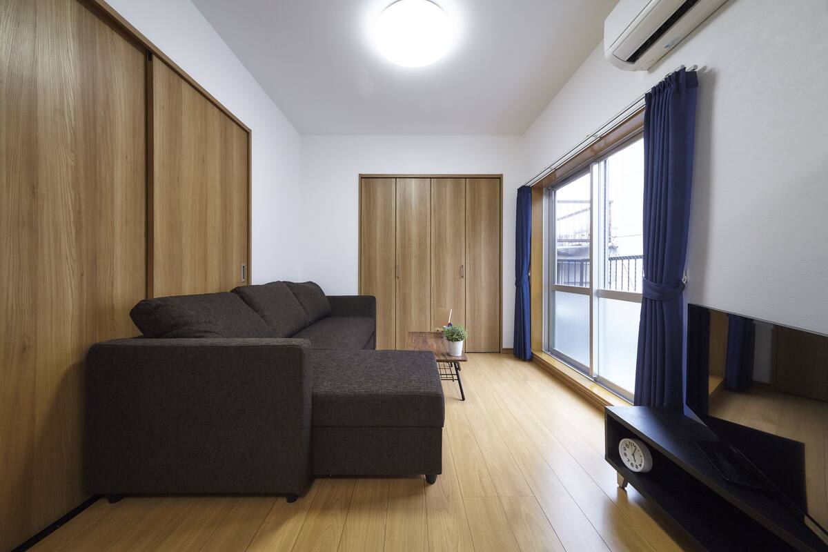 A modern living room with a sectional sofa, a small table with a plant, and a TV stand.