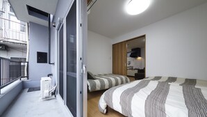 Un dormitorio moderno con dos camas, un balcón y una puerta corredera que da a una cocina.