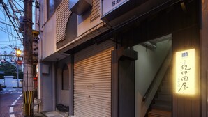 Un edificio con una persiana cerrada, una escalera que lleva a la entrada y un letrero con caracteres japoneses.