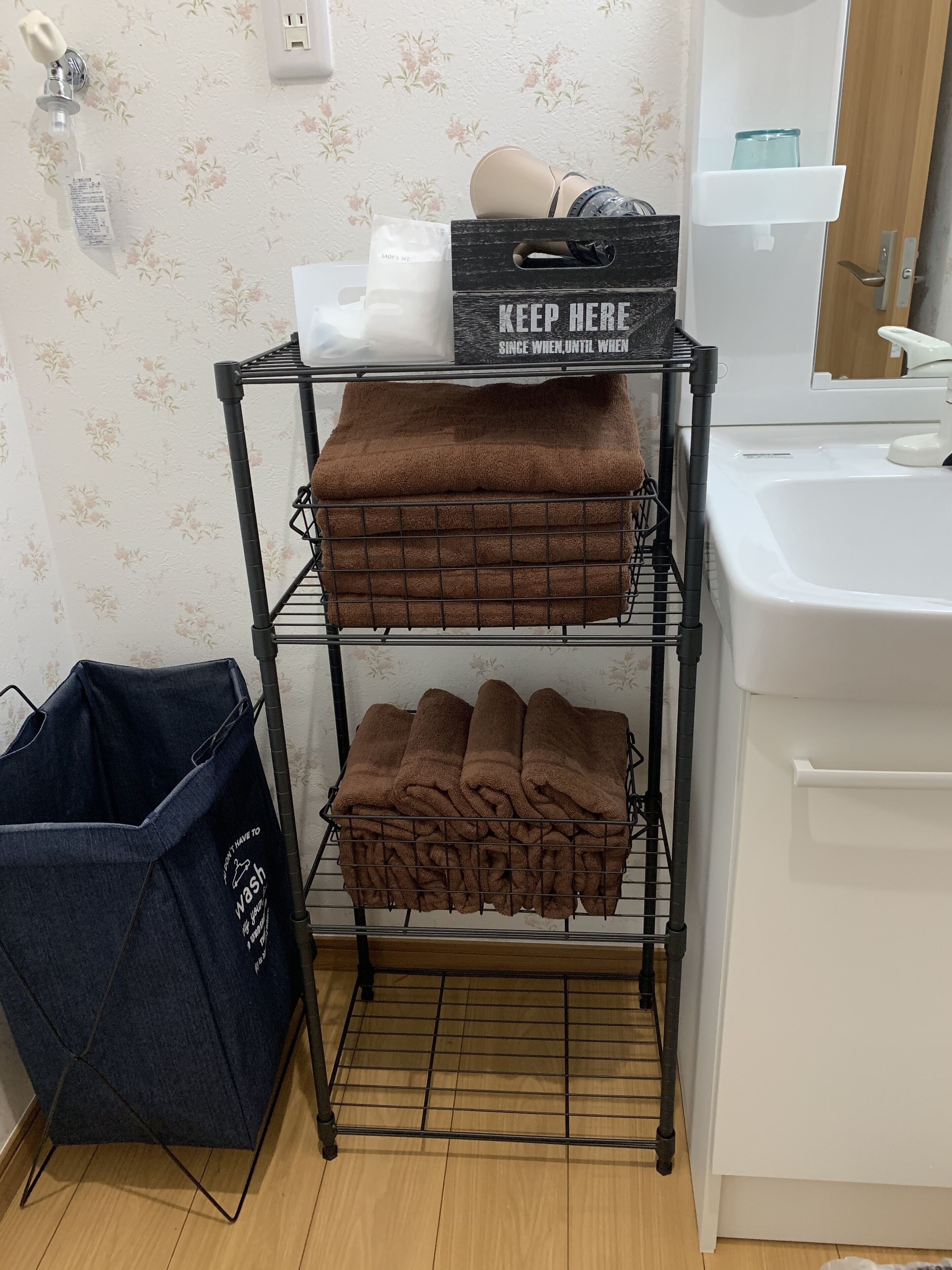 Un baño con lavamanos, espejo y un toallero con toallas dobladas.