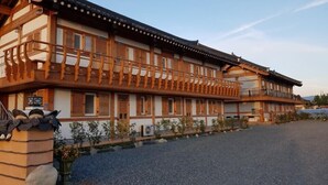 Ein traditionelles Gebäude mit einem hölzernen Balkon, einer Schotterauffahrt und einem kleinen Garten.