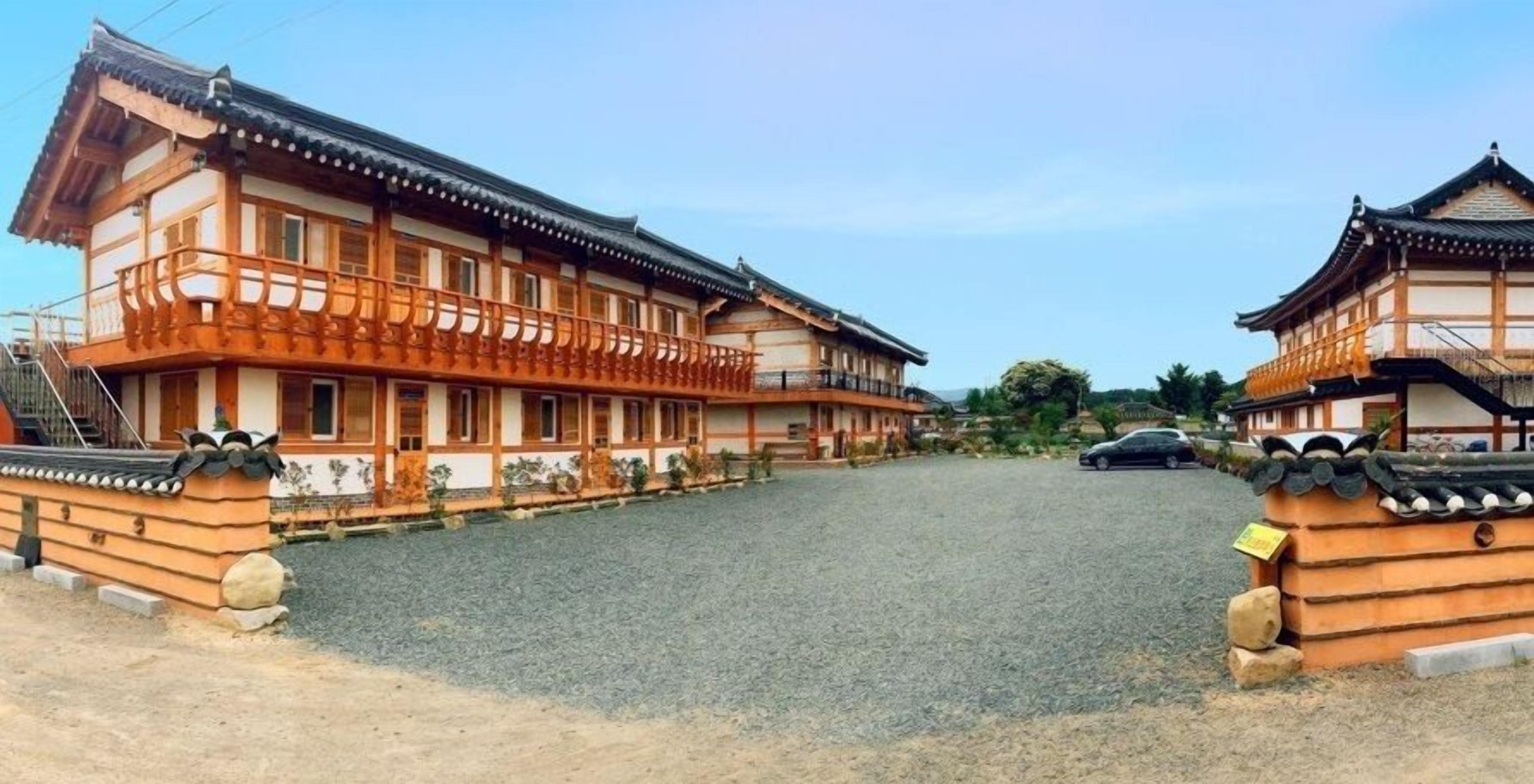 A traditional Japanese building with a wooden exterior and tiled roof, featuring a balcony and a gravel driveway.