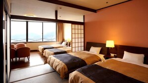 Ein Hotelzimmer mit drei Betten, einer Sitzecke und einem großen Fenster mit Blick.