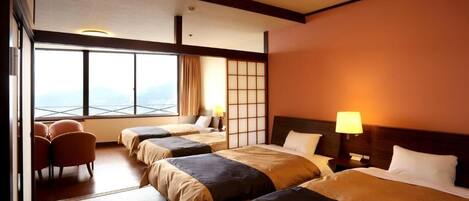 A hotel room with three beds, a seating area, and a large window offering a view.