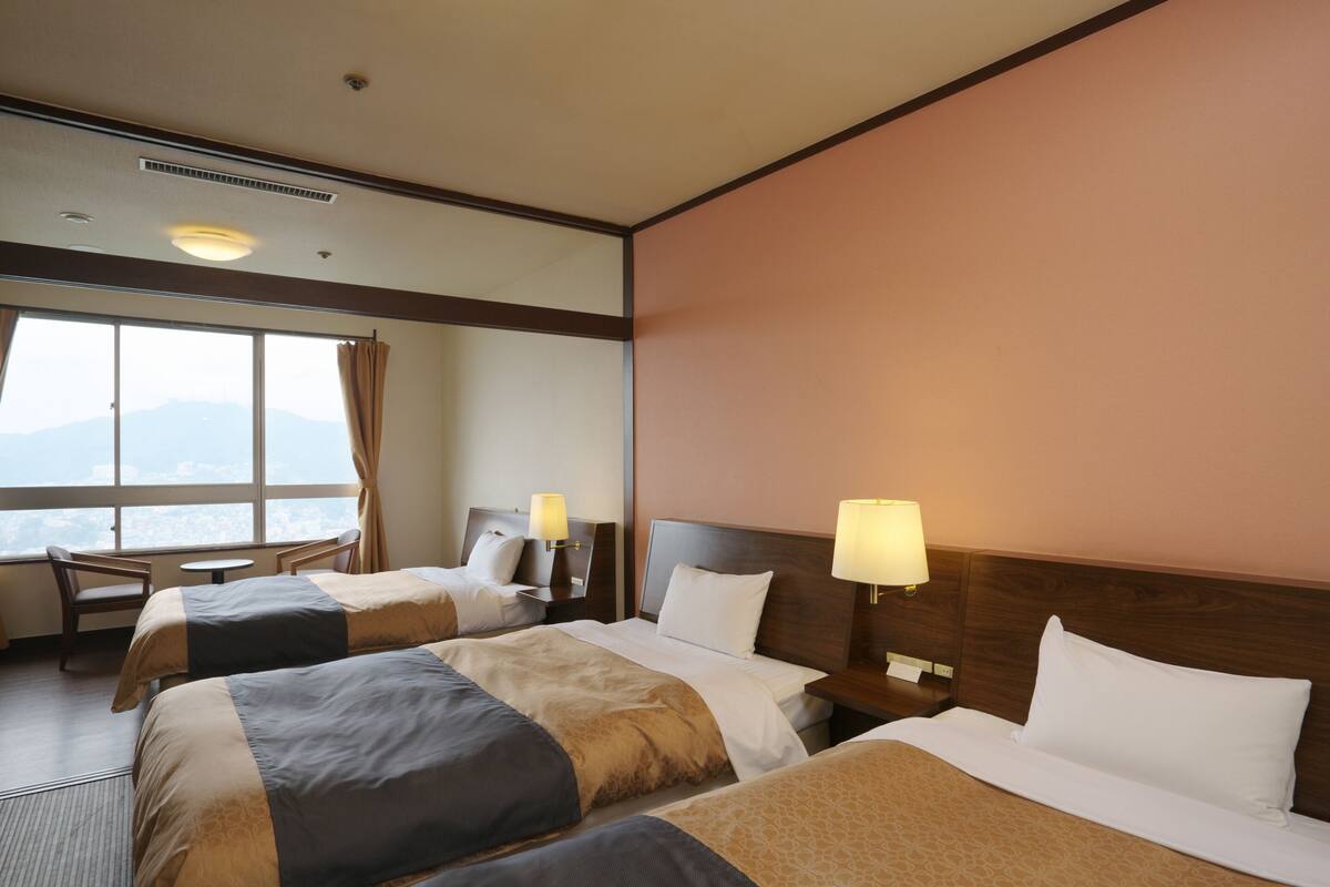 Une chambre d’hôtel avec deux lits, un bureau et une chaise.