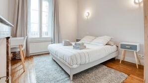 A bedroom with a bed, bedside tables, a desk, and a window with curtains. - Maison bourgeoise Haussmannienne (Gîtes de France) (Limoges)