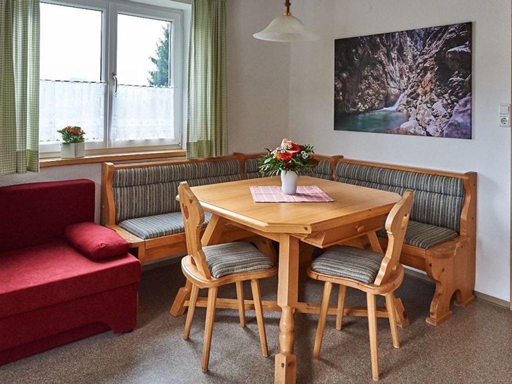 Een eethoek met een houten tafel, bankjes en een rode bank.