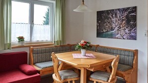 Comedor con mesa de madera, bancos y un sofá rojo.