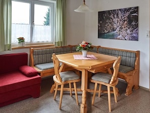 Comedor con mesa de madera, bancos y un sofá rojo.