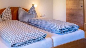 Una cama doble con ropa de cama a cuadros, una mesita de noche con lámpara y una puerta de madera.