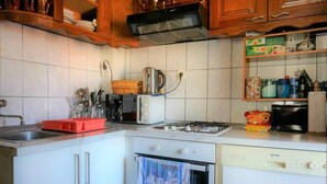 Una cocina con armarios blancos, estufa a gas, microondas y lavavajillas.