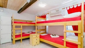 Habitación con literas, un aparador de madera y un armario blanco.