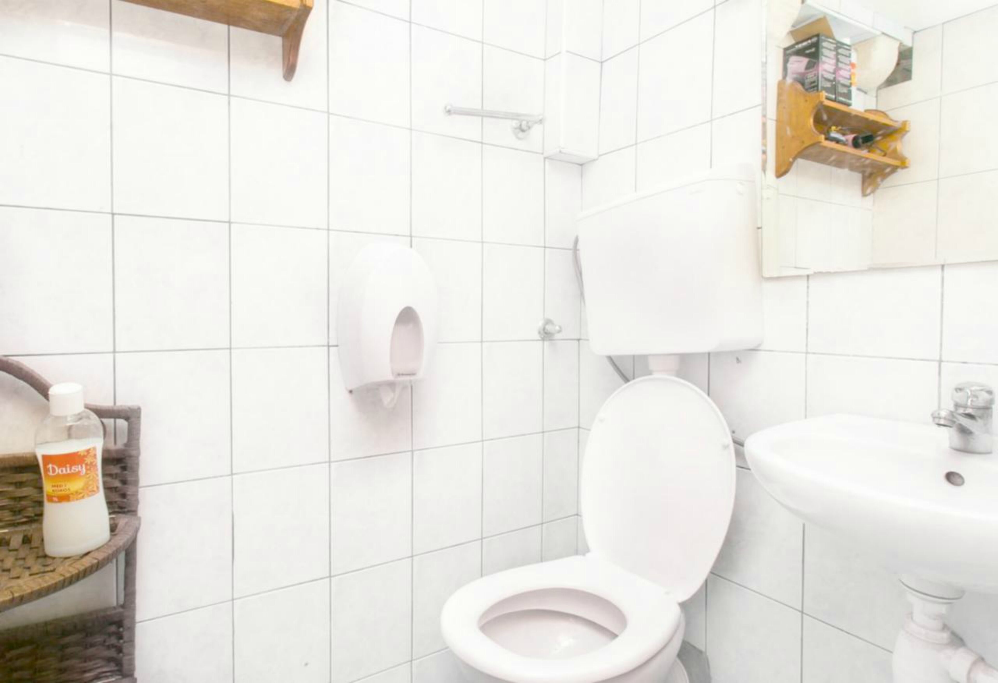 A bathroom with a toilet, sink, and a hand dryer.