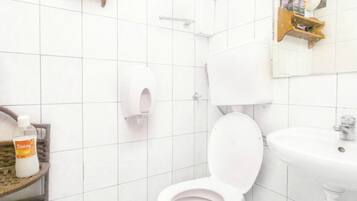 A bathroom with a toilet, sink, and a hand dryer.
