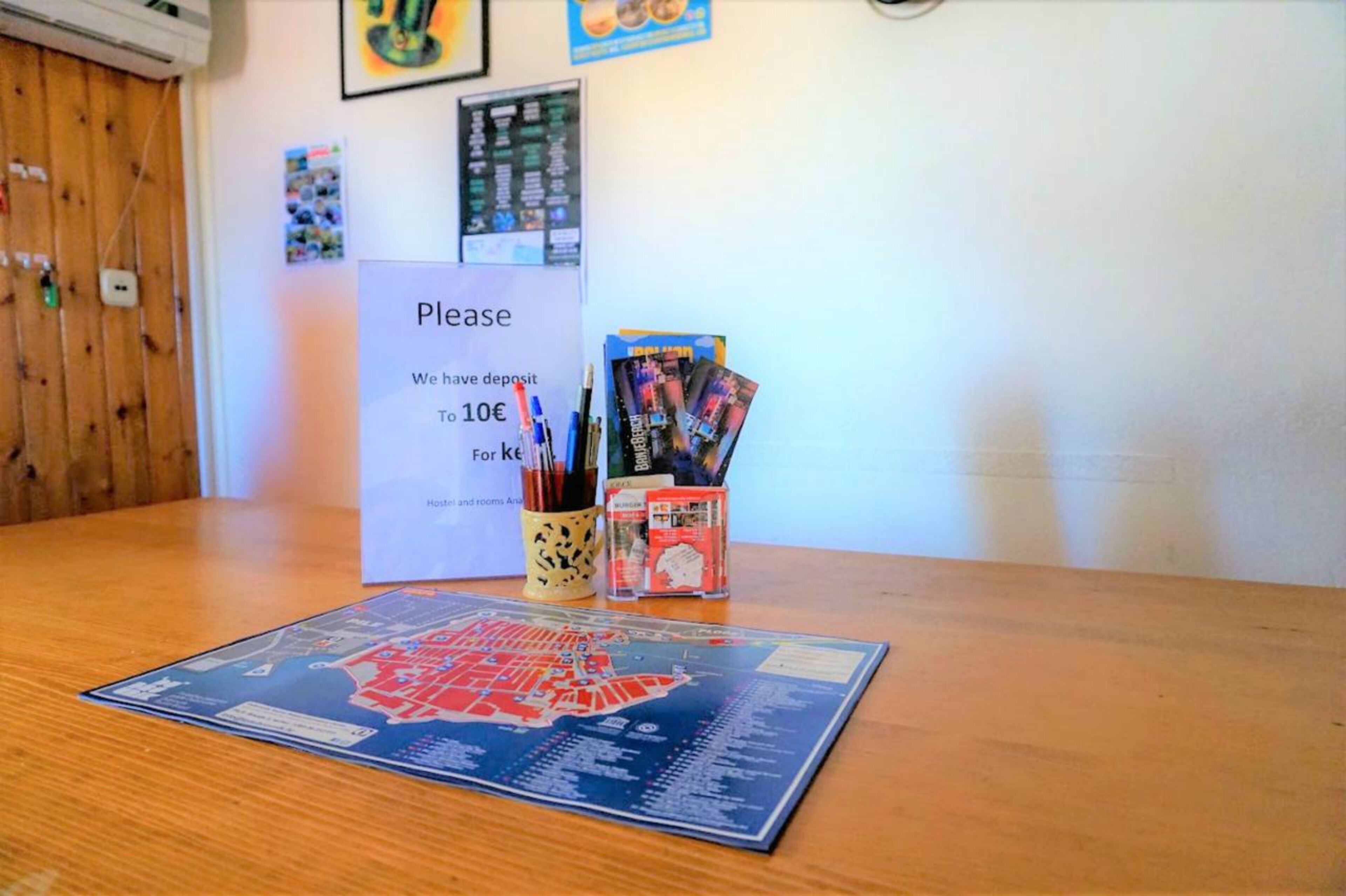 A map on a table, a sign requesting a deposit, and a mug with pens and a calendar.
