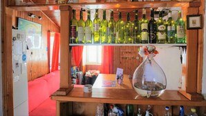 Un interior de madera con una zona de bar, estantes llenos de botellas de vino y un florero colgante.